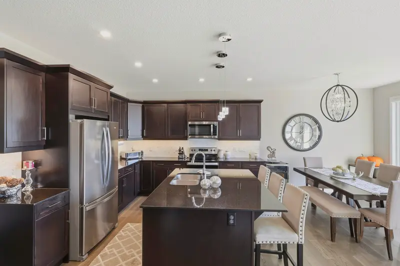 Open-concept Calgary kitchen with dark cabinetry, quartz island, and dining area