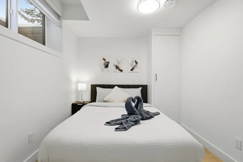 Crisp white basement bedroom with queen bed and abstract artwork