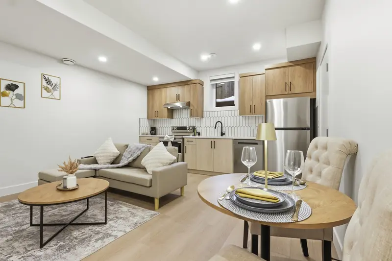 Bright basement suite with light wood kitchen, dining nook, and cozy living area