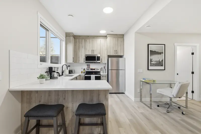 Light wood kitchen with quartz peninsula, breakfast bar stools, and home office nook