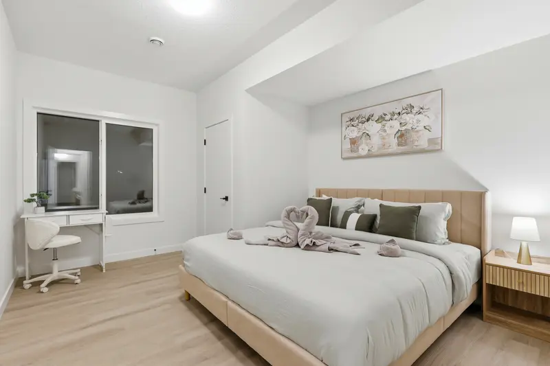 Serene primary bedroom with upholstered king bed, vanity, and floral artwork